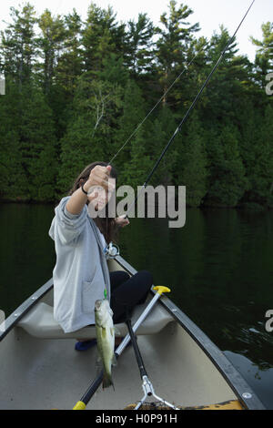 Girl fishing attraper une basse à partir d'un canoë sur un lac dans le Vermont Banque D'Images