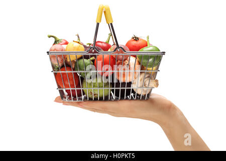 Close-up d'une main tenant un petit panier plein de légumes et fruits isolé sur fond blanc Banque D'Images