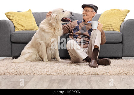 Homme mûr assis sur le plancher et de flatter son chien isolé sur fond blanc Banque D'Images