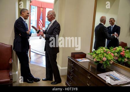 Le président américain Barack Obama et le Vice-président américain Joe Biden se reflètent dans le miroir pendant qu'ils parlent à la Maison Blanche l'Oval Office le 30 juin 2014 à Washington, DC. Banque D'Images