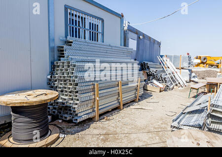 Les chemins de câbles et les tiroirs de cordon sont empilées entre container office est placé at construction site, en attente d'être utilisé dans nouvel édifice Banque D'Images