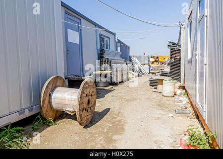 Les chemins de câbles et les tiroirs de cordon sont empilées entre container office est placé at construction site, en attente d'être utilisé dans nouvel édifice Banque D'Images