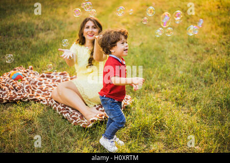 Heureux l'enfant et la femme jeux de plein air avec bulle de savon on meadow Banque D'Images