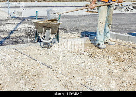 Mise à niveau est travailleur avec du gravier à la pelle nouvelle place parking en éliminant l'excès de matériau. Banque D'Images