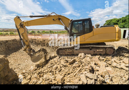 Digger excavateur jaune sur un chantier de fouilles archéologiques au moyen de lourdes pierres pour créer un espace pour la cave et les fondations d'une maison Banque D'Images