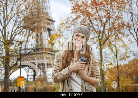 Escapades d'Automne à Paris. Portrait de jeune femme élégante près de Eiffel tower with cellphone