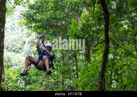 Jeune homme zoom thru une forêt nuageuse sur une aventure tyrolienne à Monteverde Costa Rica Banque D'Images