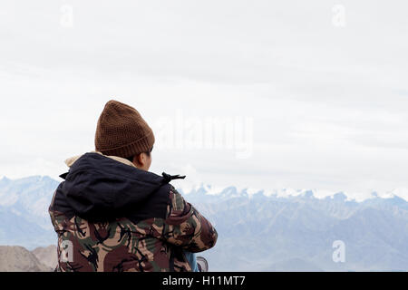 Young male traveler assis sur le sable, falaise, pensez à quelque chose à Leh, Ladakh, Inde Banque D'Images