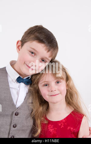 Frères et soeurs : 7 ans et plus jeune soeur âgée de 6 portant robe de soirée formelle, studio portrait isolated on white Banque D'Images