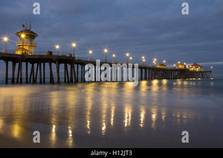 L'éclairage des feux de Huntington Beach Pier et réfléchir sur le sable et la mer à l'aube avant le lever du soleil, la lumière Banque D'Images
