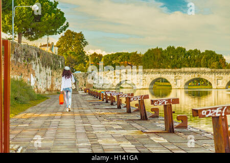 Rimini, Italie, femme marche sur le quai du canal de port près de l'ancien pont romain Banque D'Images