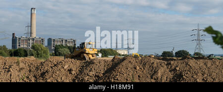 Bulldozer poussant la boue pour créer un mur autour d'une nouvelle mine. Avec la centrale électrique de KingsNorth en arrière-plan pendant la phase de démolition. Banque D'Images