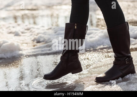 Bottes filles jambes en essayant d'aller sur la flaque de printemps Banque D'Images