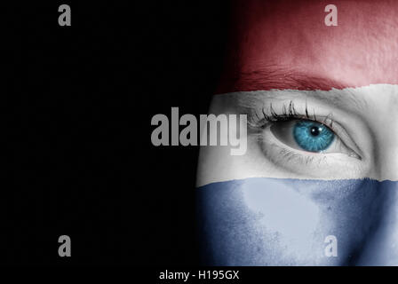 Une jeune femme avec le drapeau des Pays-Bas peint sur son visage sur son chemin à un événement sportif pour montrer son soutien. Banque D'Images