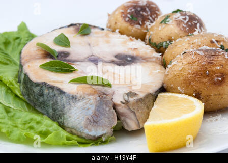 Steak de thon rouge poêlé servi avec morceau de citron et pomme de terre au four sur la plaque blanche libre. Banque D'Images