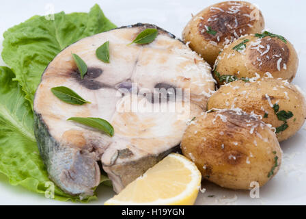 Steak de thon rouge poêlé servi avec morceau de citron et pomme de terre au four sur la plaque blanche libre. Banque D'Images