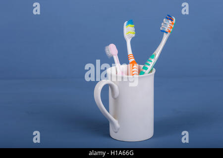 Des brosses à dents dans une tasse sur une table en bois bleu Banque D'Images