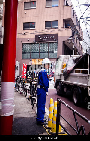 Un travailleur de la construction dirige le trafic à Tokyo, Japon Banque D'Images
