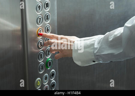 La main des femmes en appuyant sur le bouton dans l'ascenseur Banque D'Images