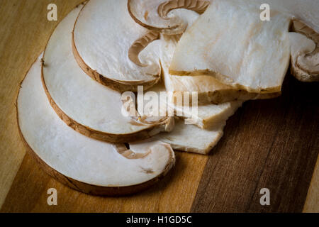 Crimini (Baby Bella) champignons, tranchés et placés dans des couches sur planche à découper en bois rayé. Pris comme un gros plan avec un objectif macro Banque D'Images