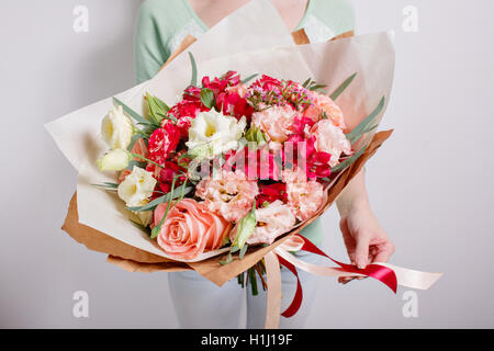 Riche bouquet de fleurs roses et rose eustoma, vert feuille dans la main bouquet frais du printemps. Fond d'été Banque D'Images