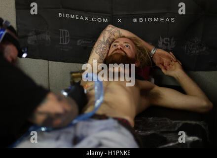 Un homme d'avoir un tatouage fait au cours de la London International Tattoo Convention au quai du tabac à Londres. Banque D'Images