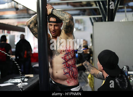 Un homme d'avoir un tatouage fait au cours de la London International Tattoo Convention au quai du tabac à Londres. Banque D'Images