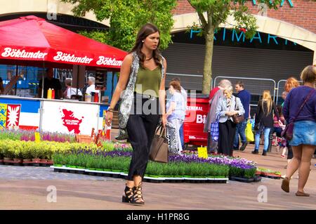 Jolie jeune femme à la mode marche à travers Carlisle Easter marché continental. Le centre-ville de Carlisle, Carlisle, Cumbria, Royaume-Uni Banque D'Images