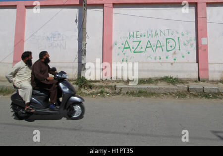 Cachemire, Inde. 29Th Sep 2016. Un scooterist ressemble à un graffiti peint par des manifestants à Srinagar, la capitale d'été du Cachemire sous contrôle indien. Affrontements entre les manifestants et la police indienne ont été signalés dans de nombreuses régions du Cachemire après les prières de la congrégation vendredi. Credit : Faisal Khan/Pacific Press/Alamy Live News Banque D'Images