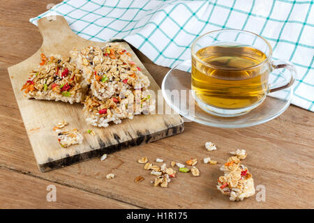 Barre granola céréales croustillantes ou des biscuits de riz avec un verre tasse de thé chaud sur la table de bois. Banque D'Images