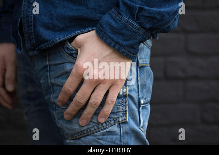 Main dans la poche de jeans pantalons contre mur arrière Banque D'Images