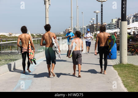 Avis de quatre jeunes hommes portant des planches sur le bord de la plage Praia do Forte dans la région de Cabo Frio, à Rio de Janeiro, Brésil. Ils vont Banque D'Images