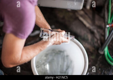 L'homme de placer les bouteilles en verre vide dans la benne Banque D'Images