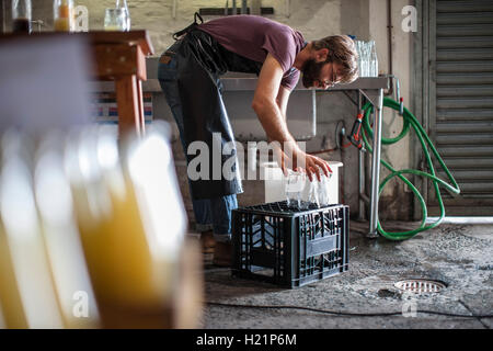 Placer l'homme nettoyer les bouteilles en verre vide sur caisse Banque D'Images