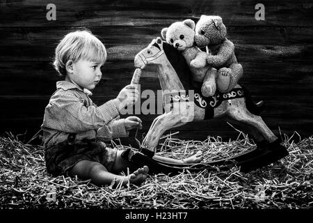 Fillette de trois ans cheval à bascule d'alimentation, teddy bears équitation, Autriche Banque D'Images