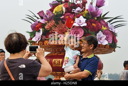 Beijing, Chine. 25 Septembre, 2016. Les touristes posent pour des photos en face de la principale parterre de fleurs à la place Tian'anmen dans le centre de Pékin, capitale de la Chine, 25 septembre 2016. Les parterres affichée à la place Tian'anmen et le long de l'Avenue Chang'an ont achevé l'installation par dimanche pour la journée nationale, qui tombe le 1 octobre. Cette année, les grandes fleurs en forme de panier parterre est de 50 mètres de diamètre et 17 mètres de hauteur. Crédit : Li Xin/Xinhua/Alamy Live News Banque D'Images