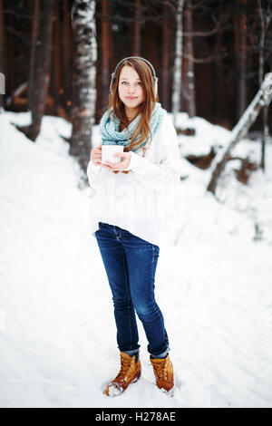 Belle femme de boire une boisson chaude en hiver Parc. Vacances d'hiver. Pleine hauteur, looking at camera. Le paysage d'hiver Banque D'Images