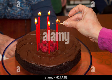 Cinq bougies allumées sur le chocolat un gâteau garni de framboises. St Paul Minnesota MN USA Banque D'Images