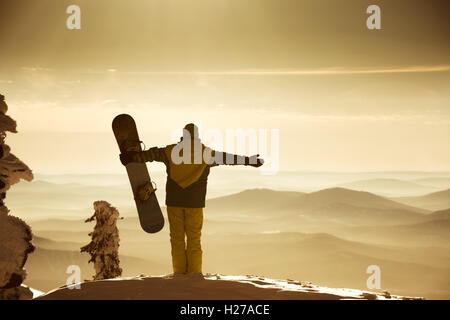 Snowboarder posant sur fond de ciel bleu brouillard montagnes Banque D'Images