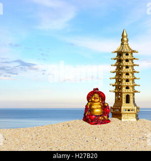 Laughing Buddha et pagode de 7 étages dans le sable. Symbole de chance et de la prospérité dans le Feng-Shui Banque D'Images