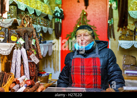 Riga, Lettonie - 24 décembre 2015 : femme lettone sur la photo tout en vendant des friandises traditionnelles et de l'alimentation à la Riga Marché de Noël. Il y a les gens pouvaient trouver des saucisses lettone, tartes et pains. Banque D'Images