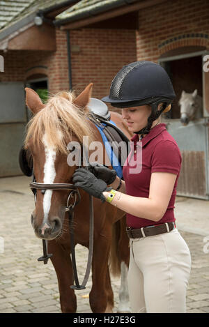 La préparation d'un jeune cavalier poney pour sa circonscription leçon - Septembre 2016 - Adolescent réglage de la bride Banque D'Images