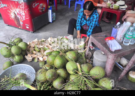 Nha Trang, Vietnam - 7 Février 2016 : une vietnamienne est à la noix de coco pour les voyageurs à un vendeur de rue Banque D'Images