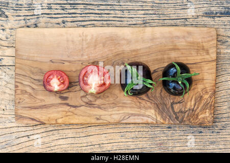 Solanum lycopersicum. Les tomates noires entières et des moitiés de Rose Indigo sur bois Banque D'Images