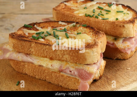 Deux tranches de croque-monsieur au fromage et jambon sur une planche en bois Banque D'Images