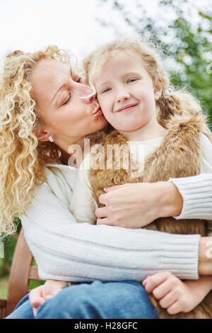 Happy mother kissing et embrassant fille avec amour en automne Banque D'Images