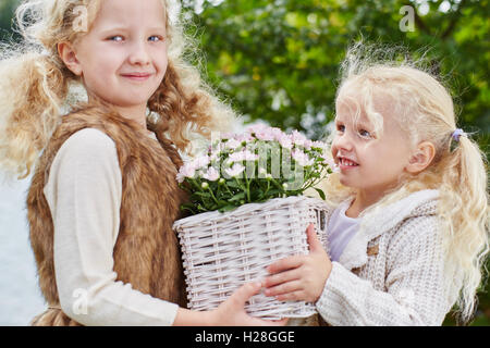 Deux filles avec panier de fleurs au cours de jardinage en automne Banque D'Images