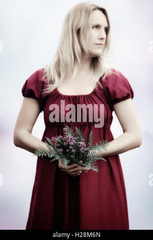 Une femme dans une robe rouge avec un bouquet de fleurs Banque D'Images