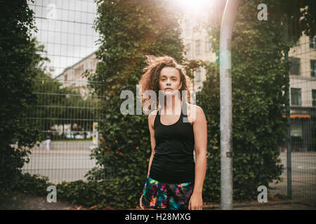 Portrait de belle jeune fille debout sur un terrain de basket-ball et à partir de l'appareil photo. Hipster dans l'emploi temporaire. Banque D'Images