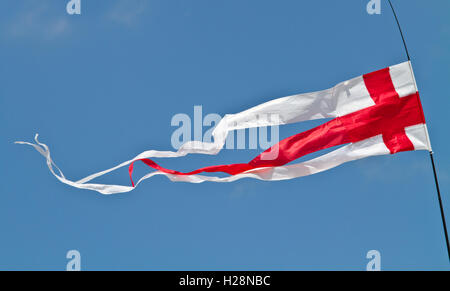 Le drapeau anglais, la croix rouge de St George, battant comme un fanion contre un ciel bleu sur une journée ensoleillée Banque D'Images